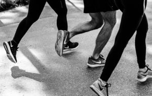 legs and feet of three runners on sidewalk